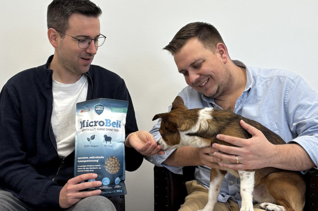 Two men feeding a dog